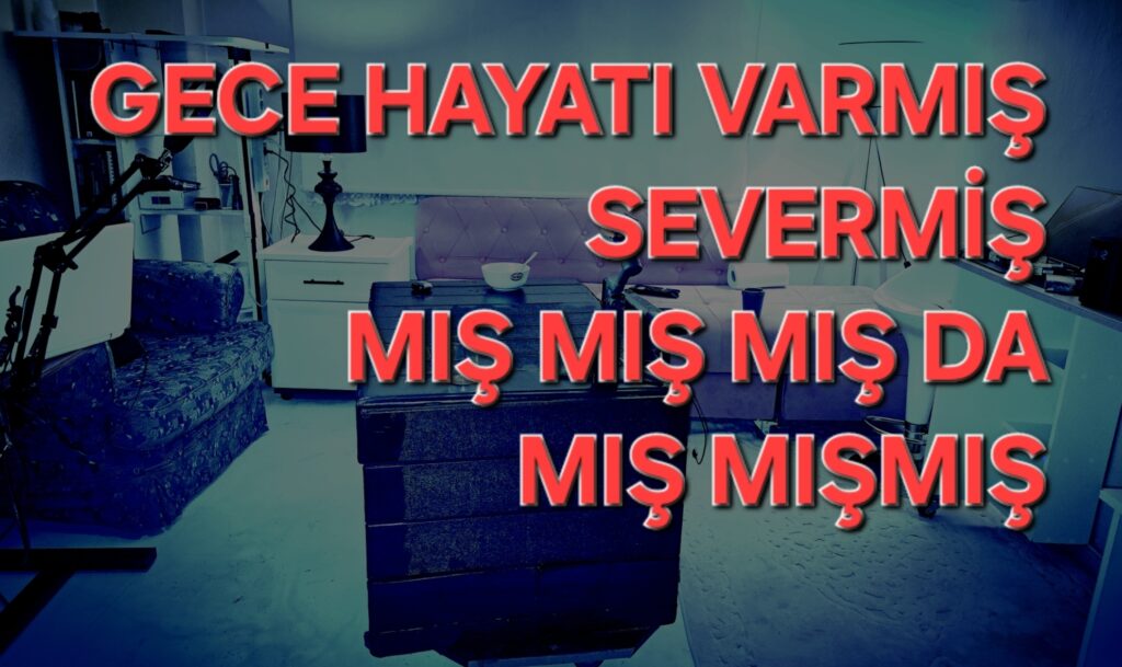 Bir oturma alanı ve masanın yer aldığı, üzerinde 'Gece hayatı varmış severmiş' yazılı büyük harflerle süslenmiş bir iç mekan görüntüsü.